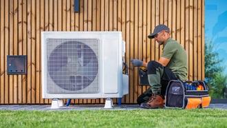 uomo con trapano che lavora su motore della pompa di calore